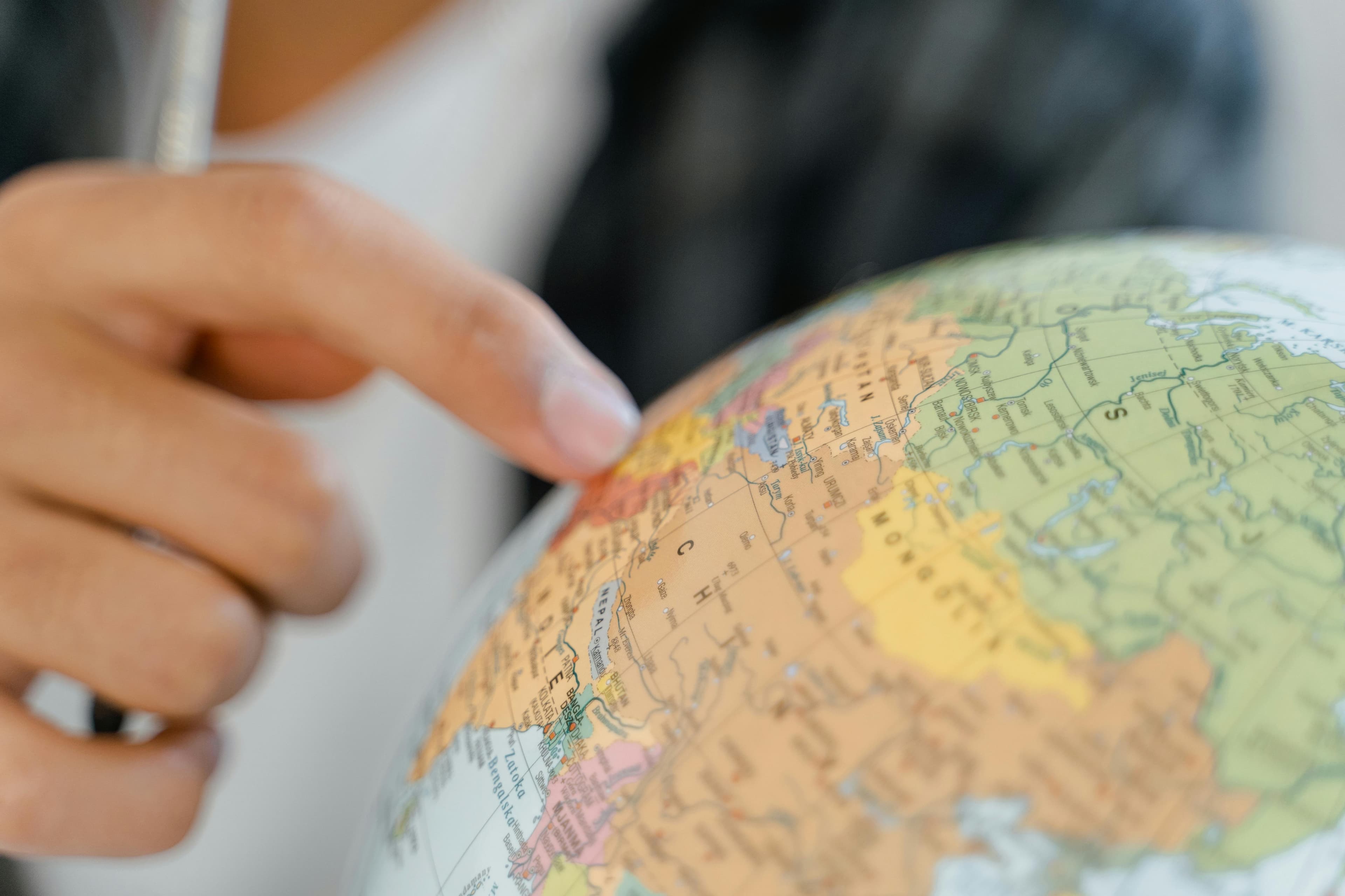 A hand pointing to a location on a globe