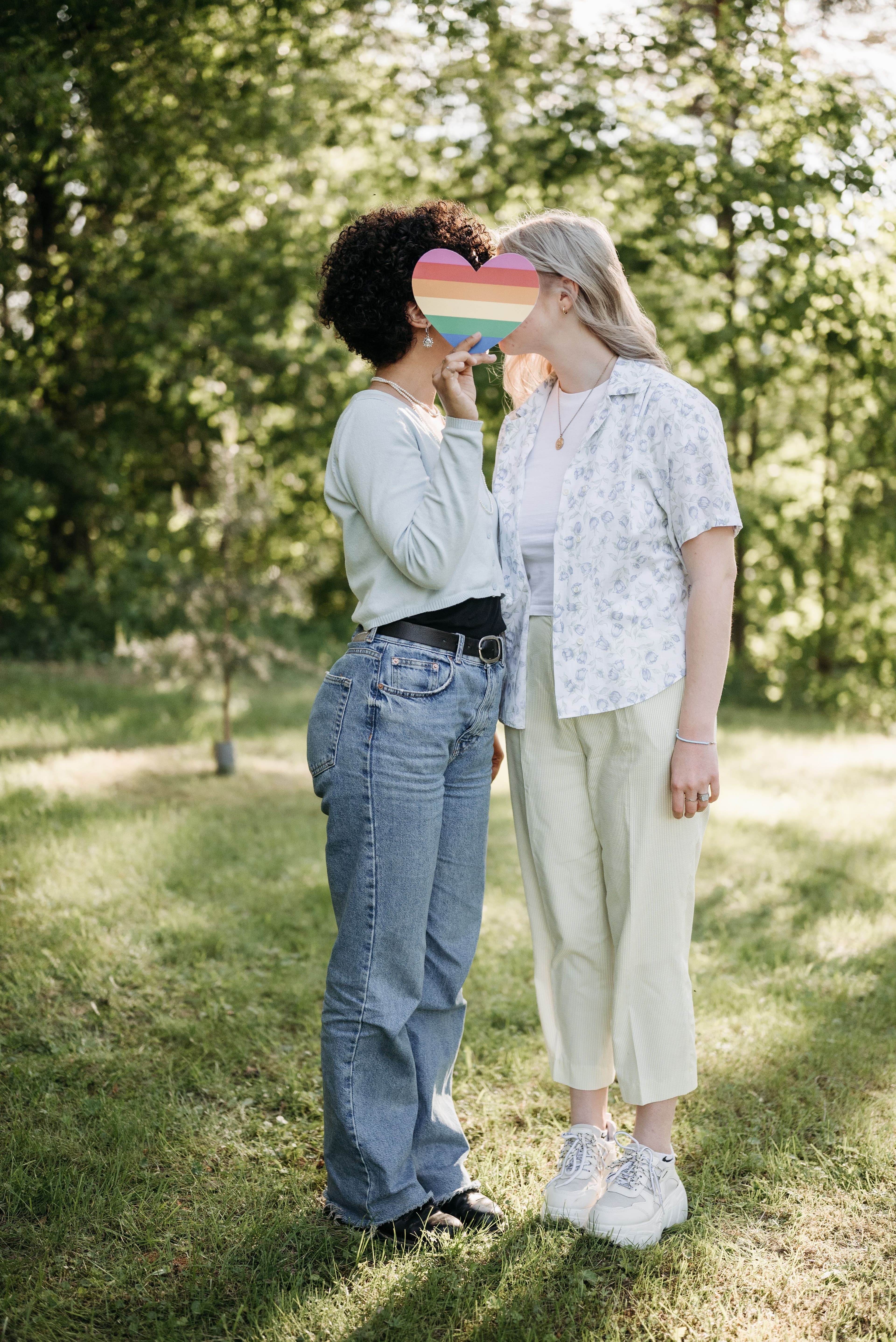 A couple holding a rainbow heart outdoors