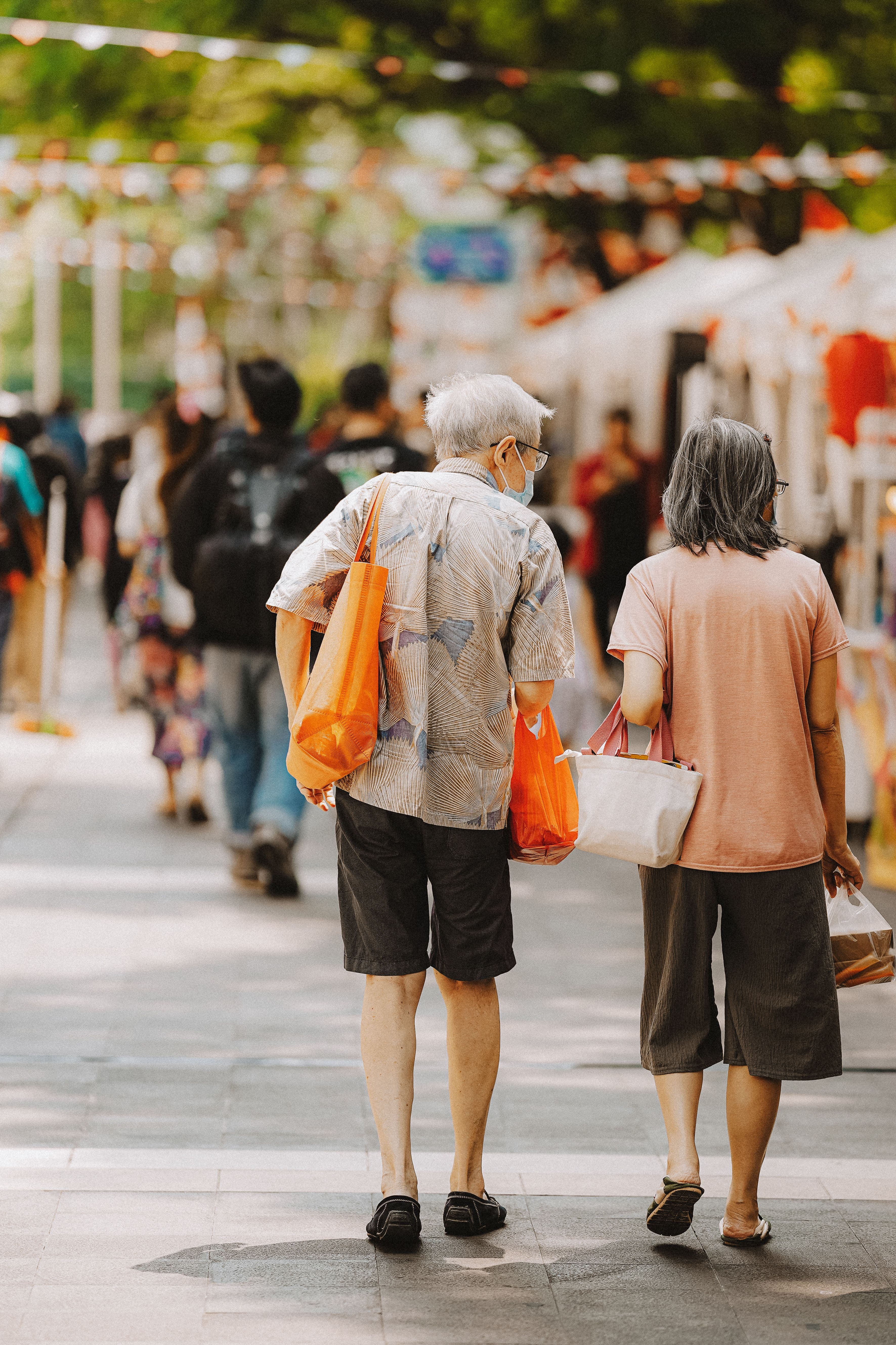 An older couple walking through a lively city